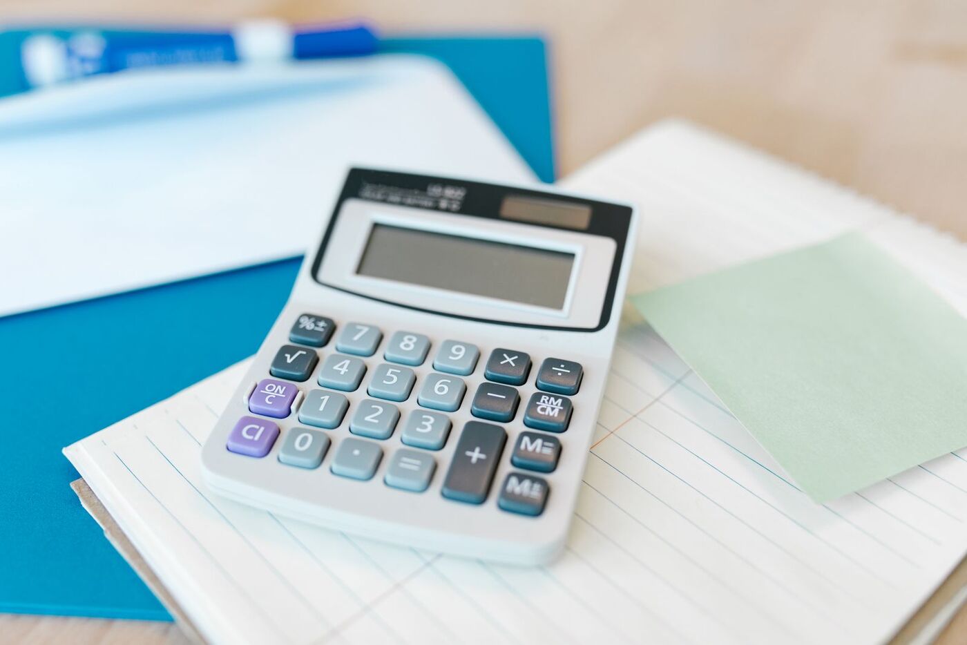 A calculator resting on lined paper and a blue folder