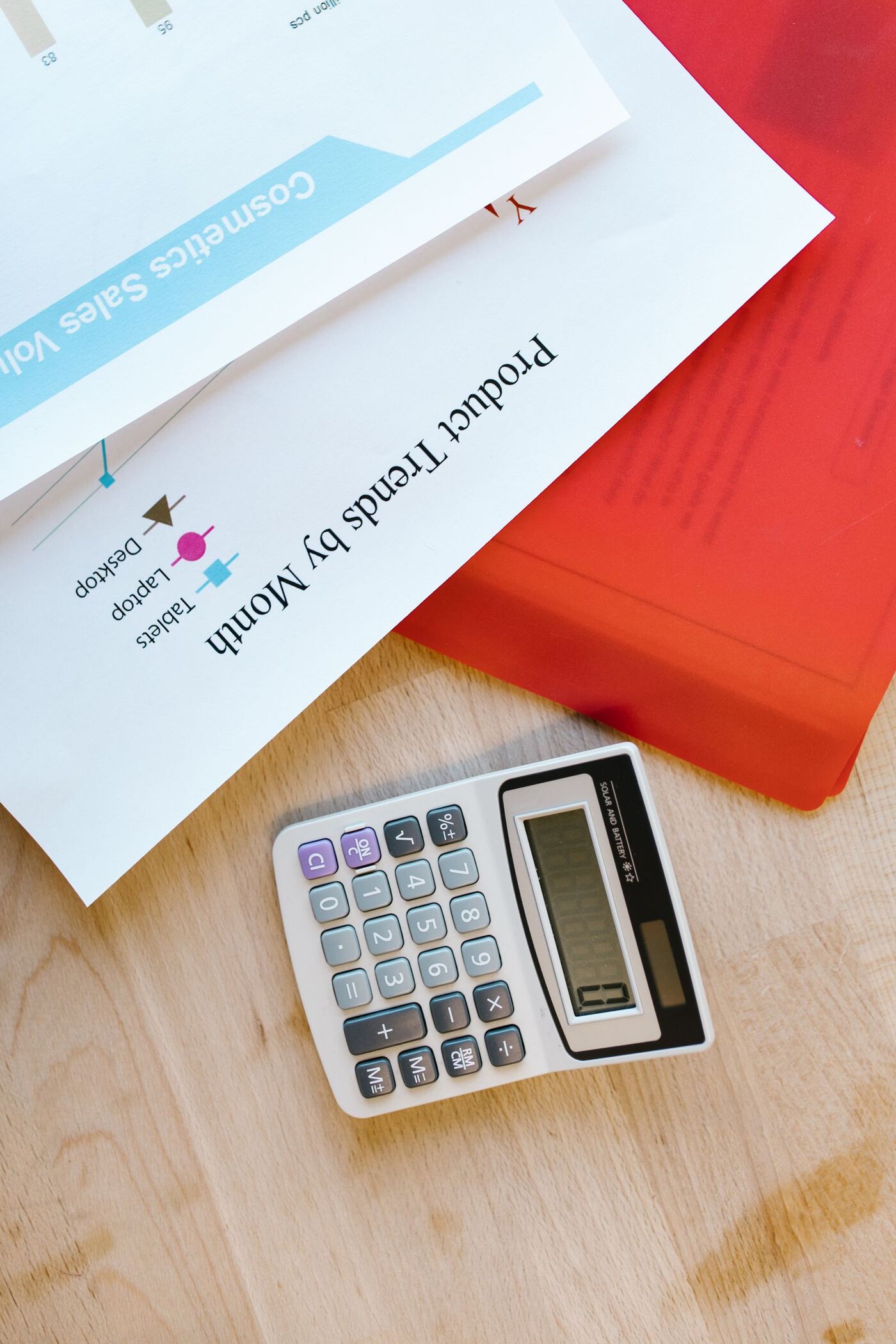 A calculator and printed charts on a wooden desk
